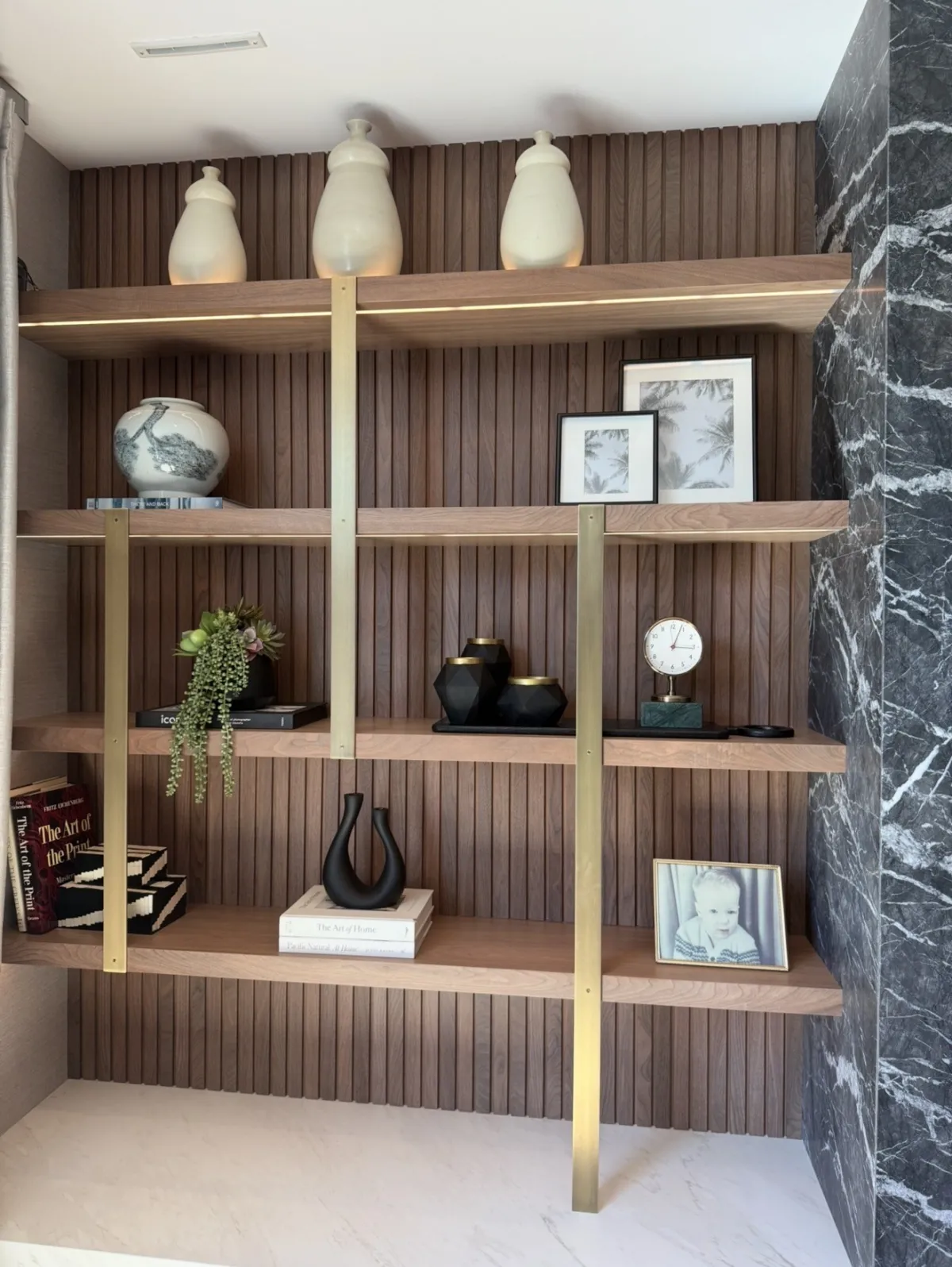 Wood shelving with ceramics, books, framed art, and sculptural objects
