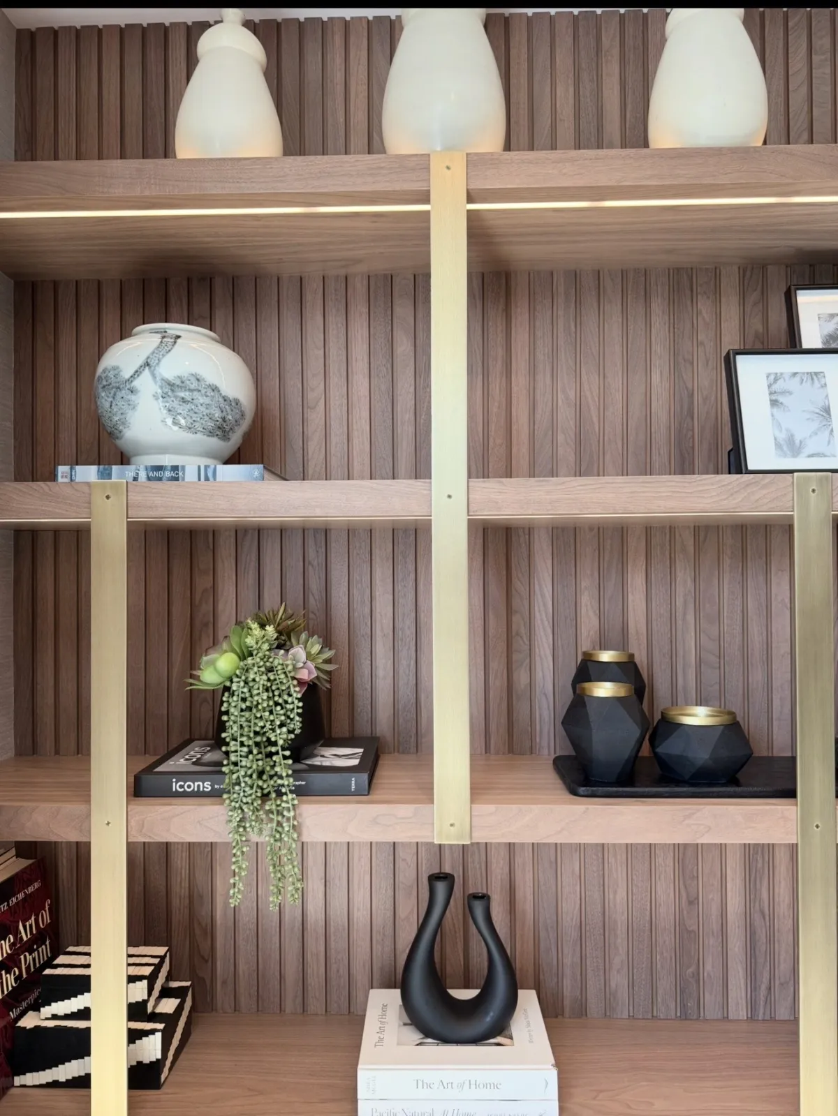 Detail of styled wood shelves with pottery, greenery, and black vessels