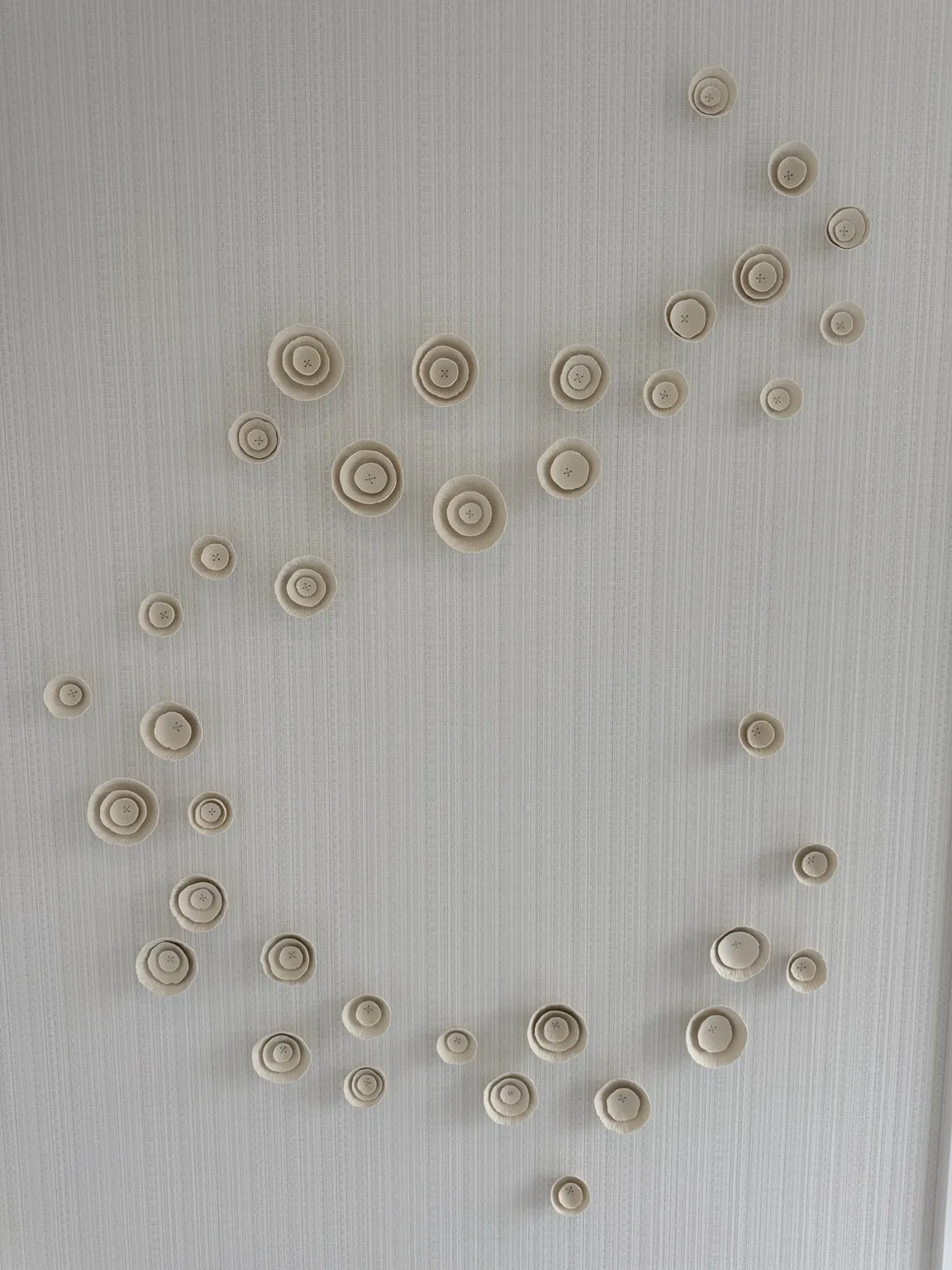 Close-up of sculptural circular wall art on textured wallpaper