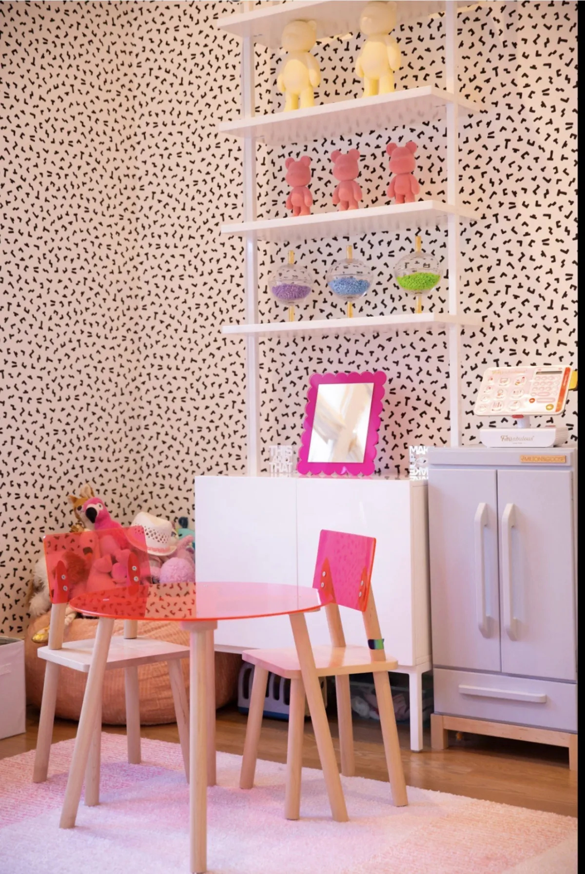 Playful children’s corner with patterned wallpaper and white shelving