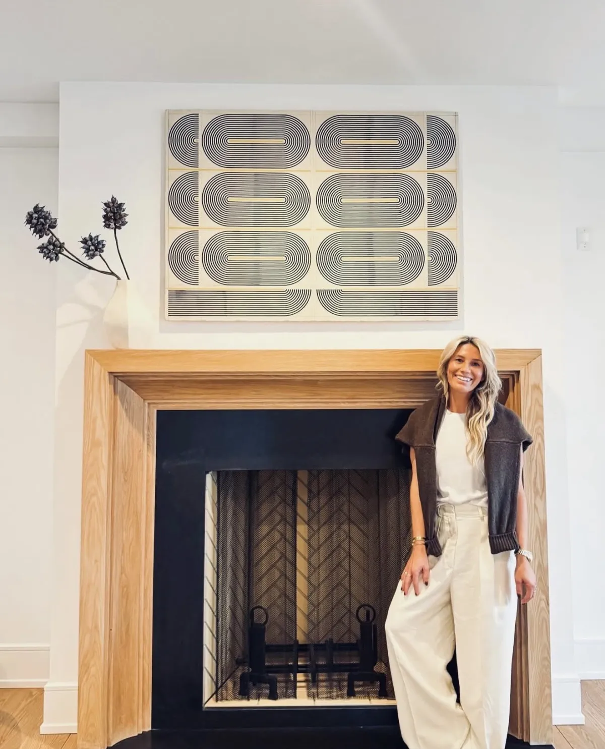 Marisa beside a wood-framed fireplace and graphic artwork