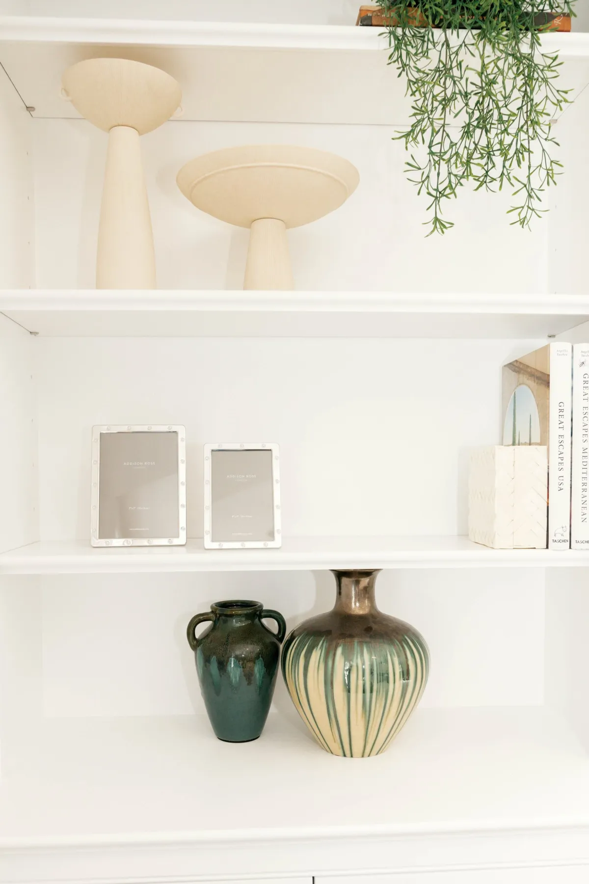 Neutral decor and green ceramics arranged on white built-in shelves