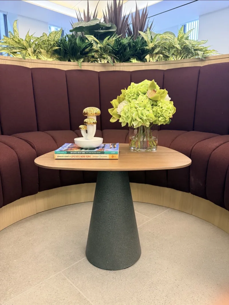 Plum channel-tufted banquette with hydrangeas and art books on a round café table