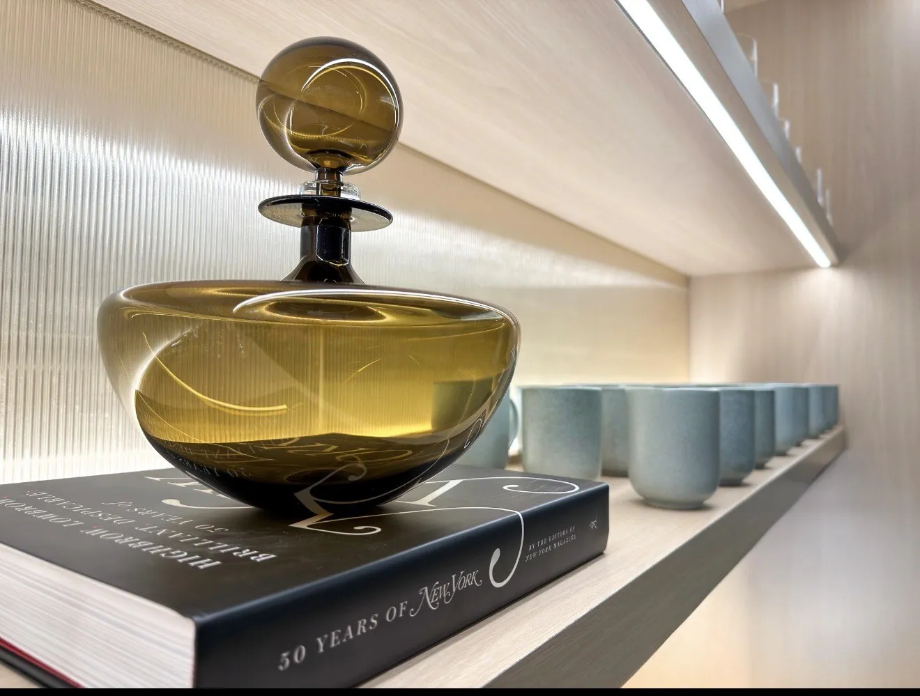 Amber glass vessel on a New York book beside blue ceramic mugs
