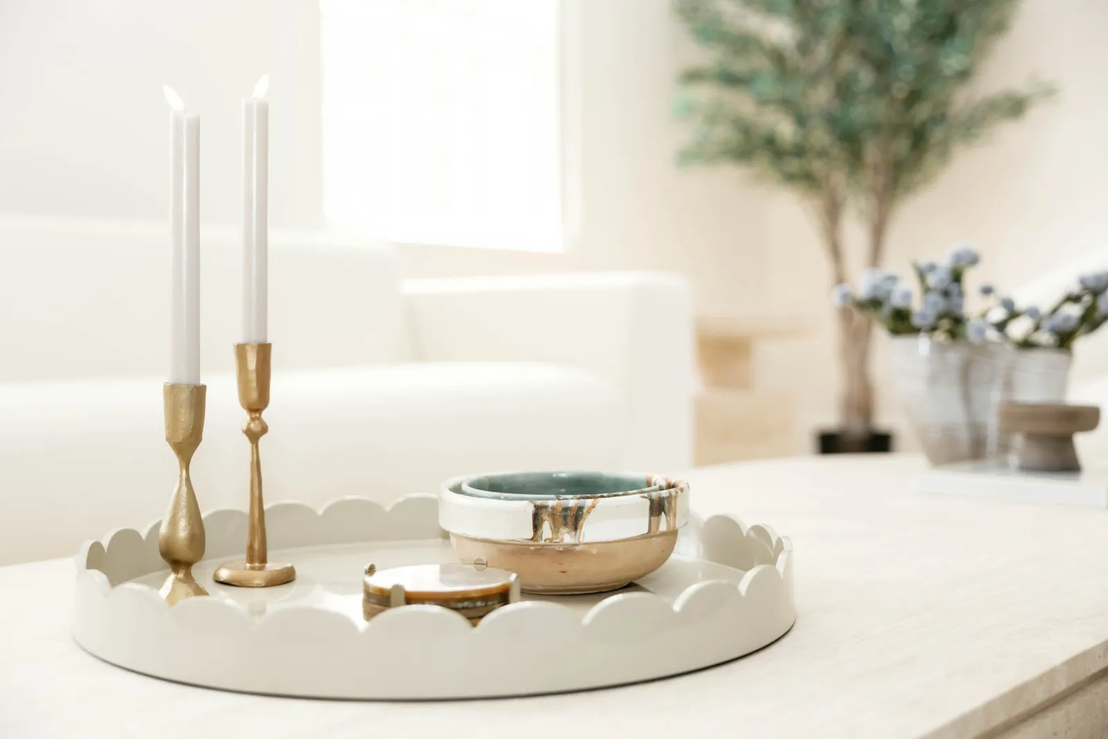 Brass candlesticks and ceramic bowl on a white scalloped tray