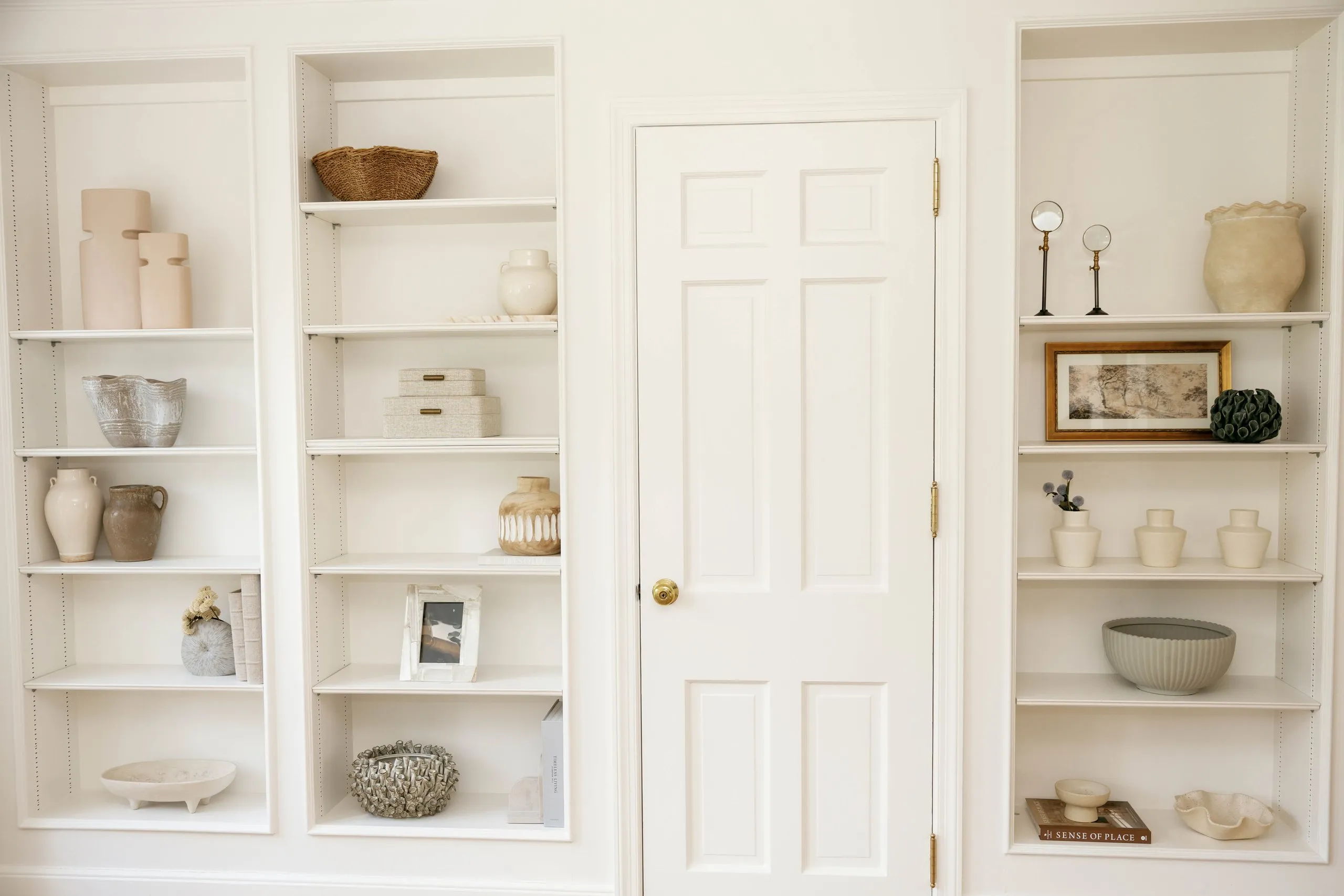 White built-in shelves styled with neutral ceramics and artwork in a Short Hills home