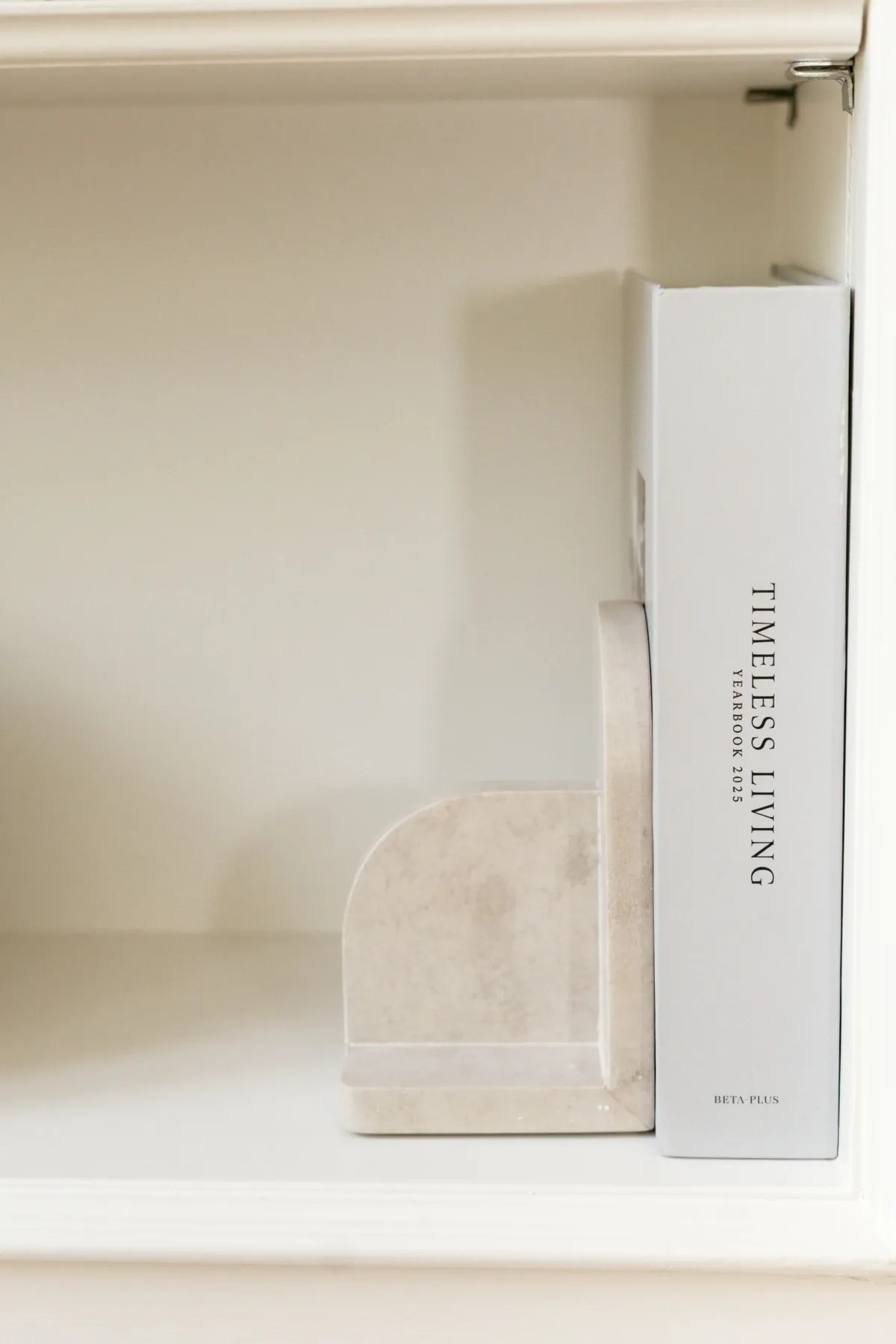 Sculptural bookend beside a design book on a white shelf