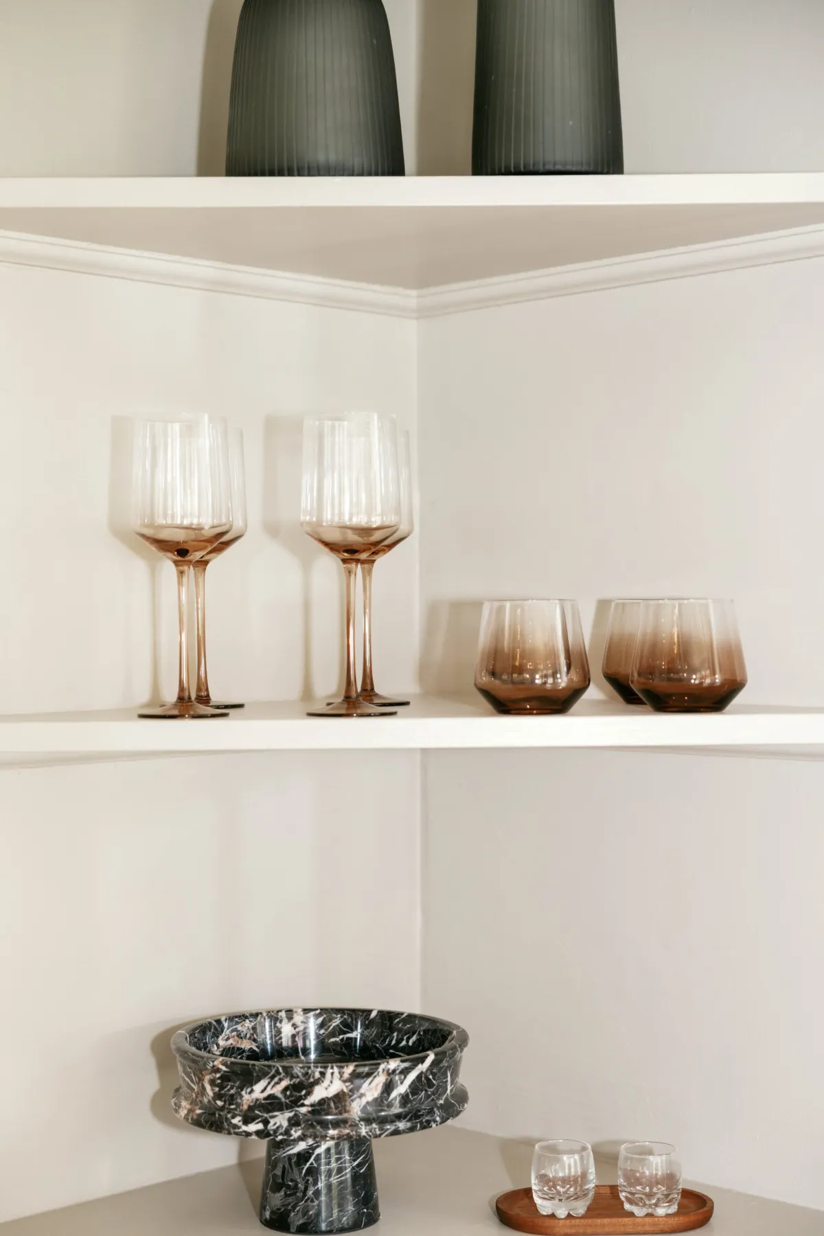 Rose glassware and black marble bowl on white bar shelves