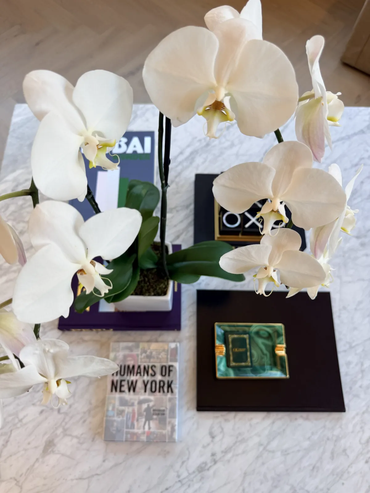 Orchids over Humans of New York and a malachite tray on a marble table